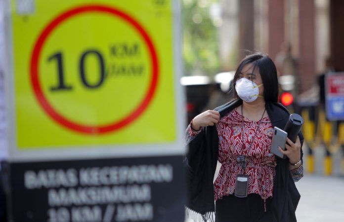 Seorang wanita menggunakan masker saat keluar dari gedung BRI 2, Jakarta, Kamis (23/1/2020).