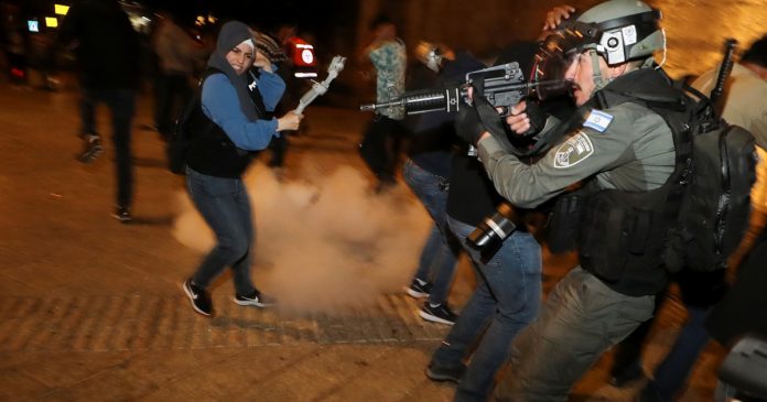 Israeli police officer stands in position as a stun grenade explodes by the gate to Jerusalem's Old City