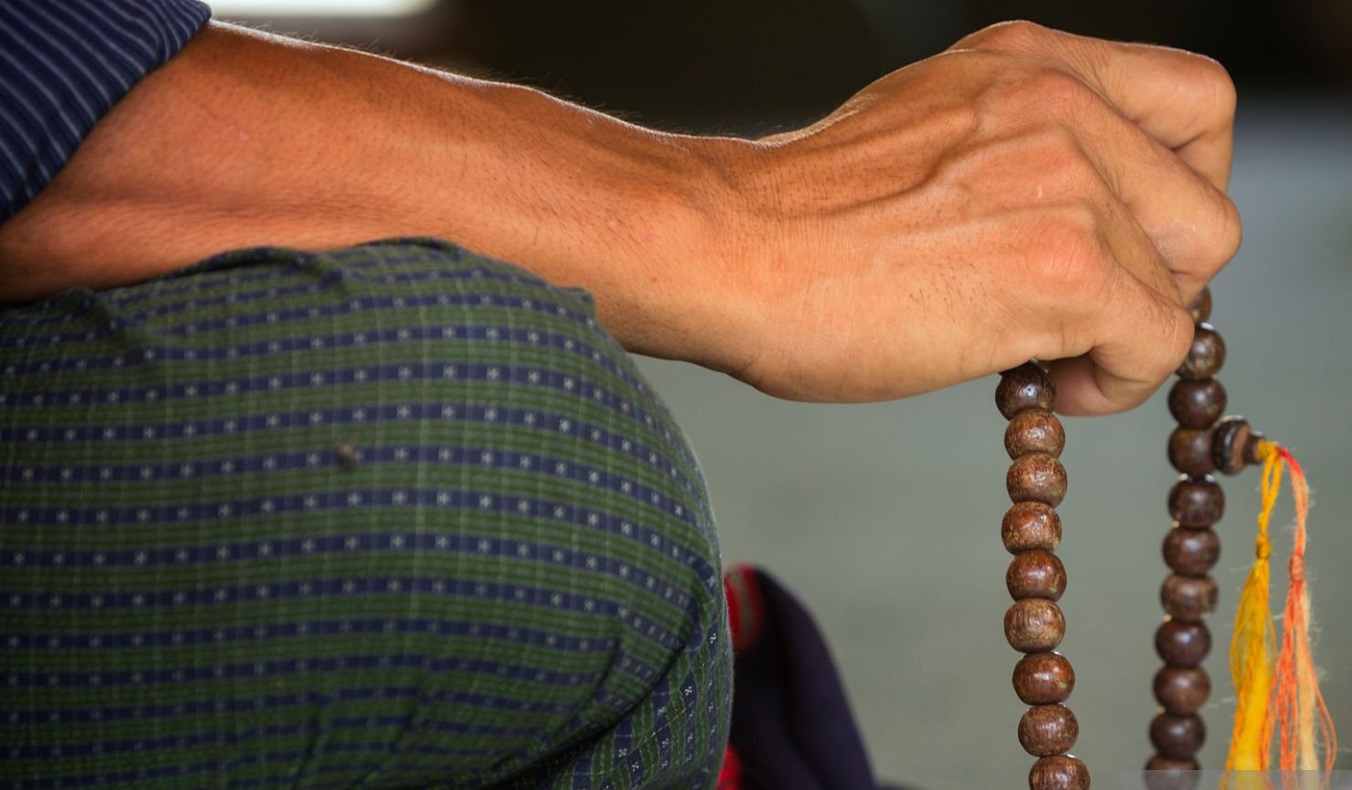 A man holds rosary beads while at prayer in Sule Paya.